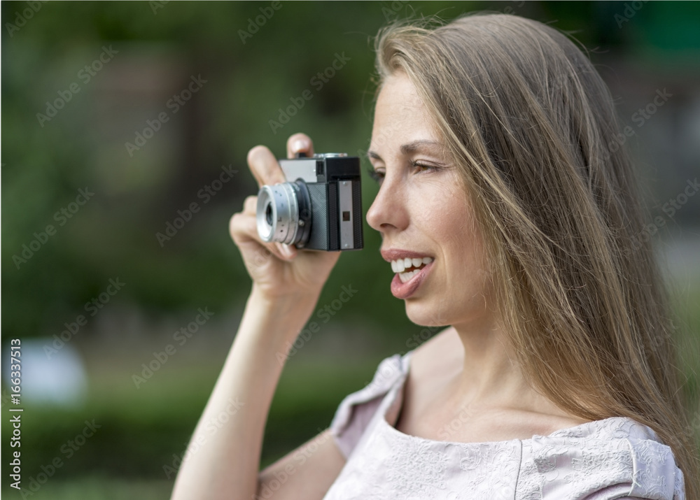 Beautiful woman is taking picture with old fashioned camera, outdoors. Beautiful woman is taking picture with old fashioned camera, outdoors.