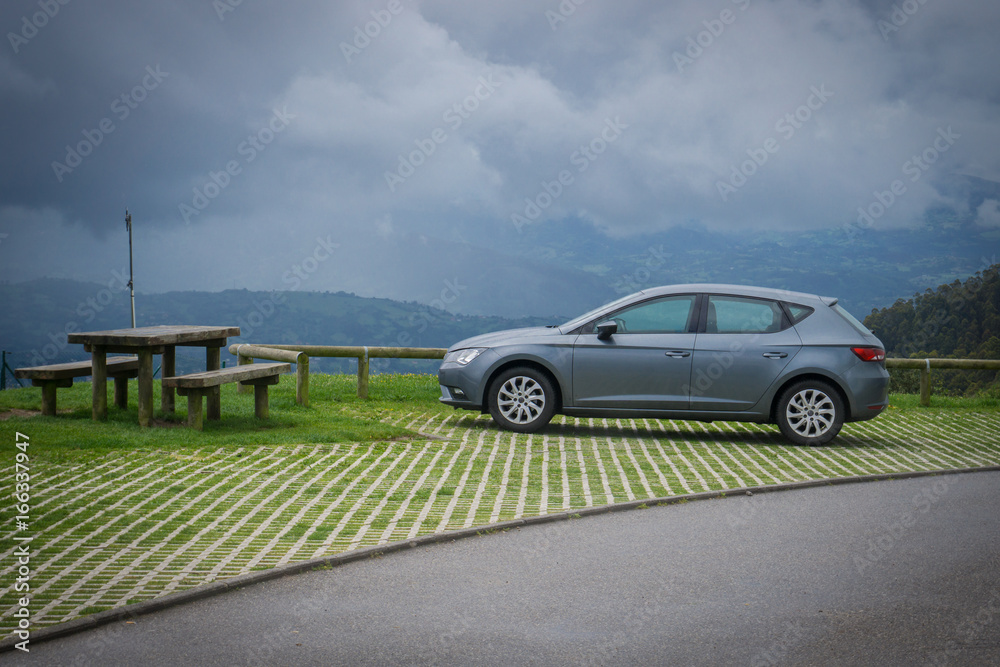 Amazing landscape with thunderstorm sky, dark clouds and a car near a camping table in summer rainy day