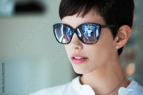 Young beautiful woman at optician with glasses buying sunglasses