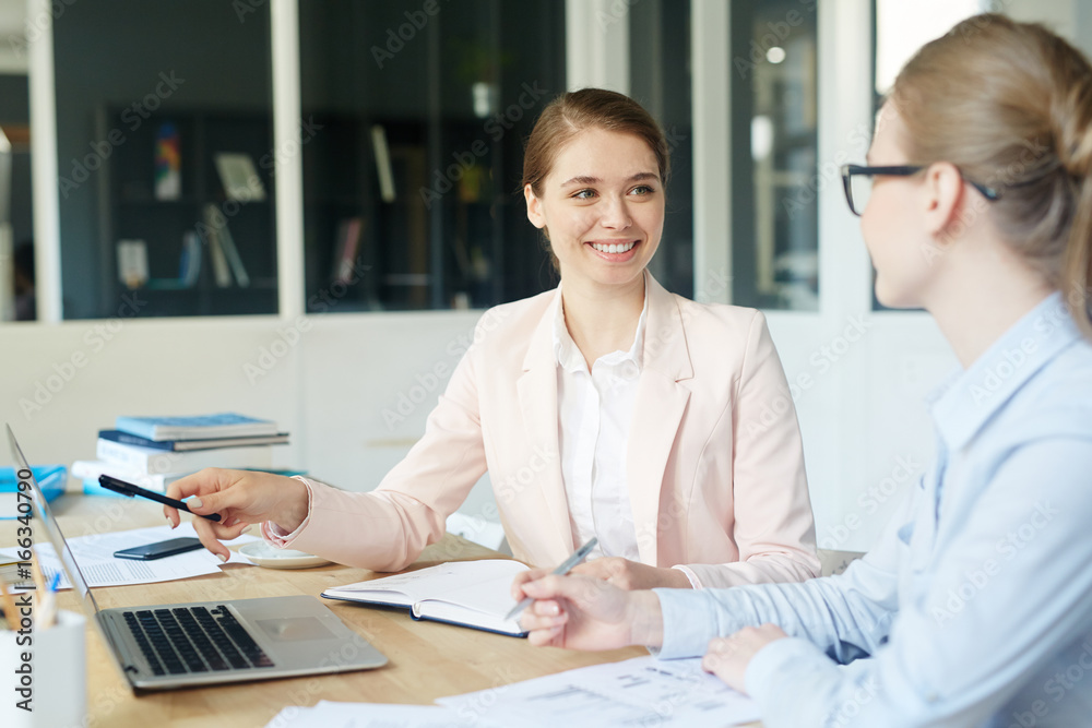 Start-up meeting of two confident businesswomen - discussing project or analyzing data Start-up meeting of two confident businesswomen - discussing project or analyzing data