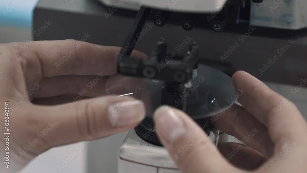 Unrecognisable woman optimetritian put round glass lens in measuring machine on bright laboratory table Unrecognisable woman optimetritian put round glass lens in measuring machine on bright laboratory table