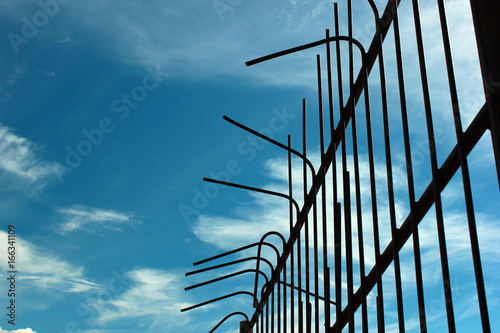 Φωτογραφία Old bent metal fence against blue sky background
