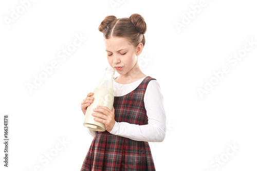 Portrait of cute girl in school uniform posing with milk bottle against white background