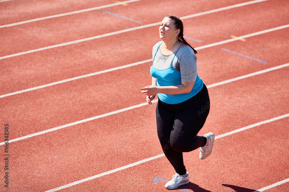 Obraz premium Very tired fat young woman having cardio training in hot weather on stadium