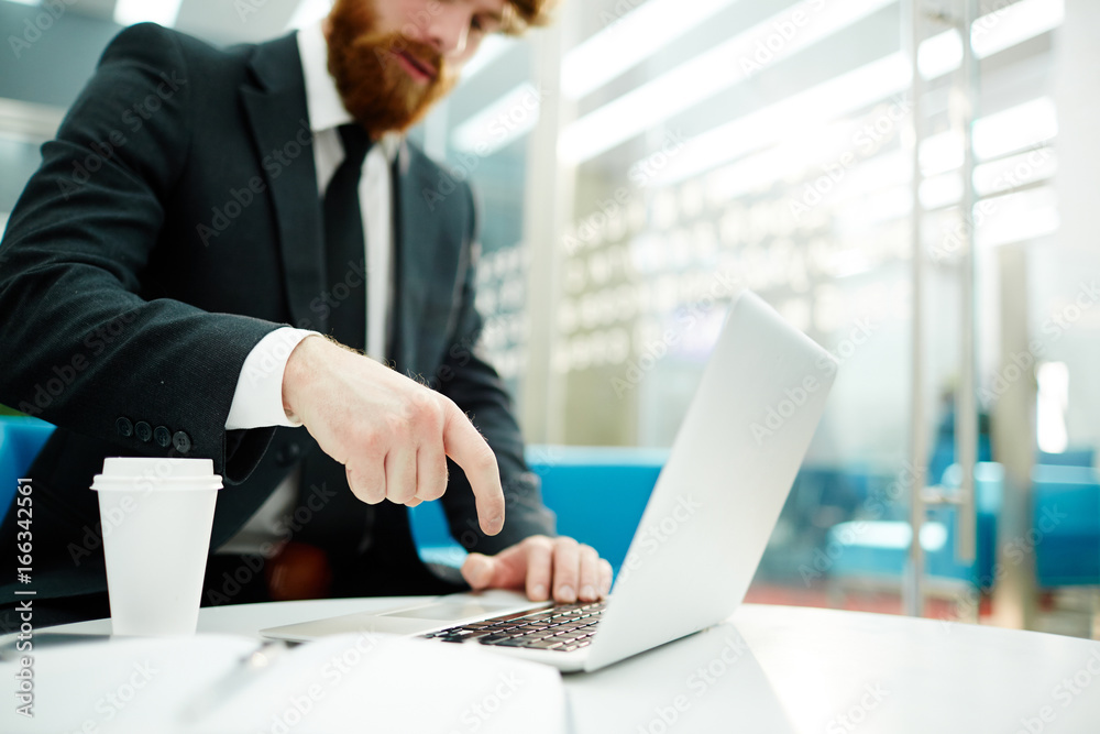 Closeup shot of businessman pressing button on laptop keyboard while working in modern office Closeup shot of businessman pressing button on laptop keyboard while working in modern office