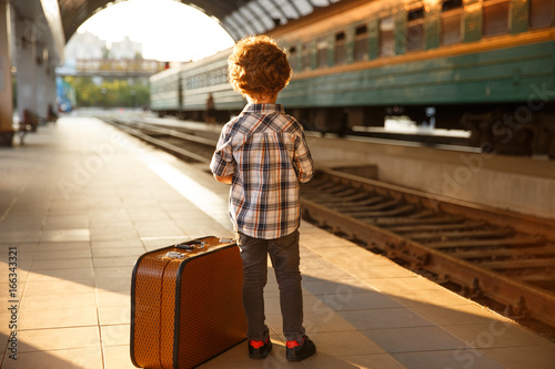 Stylish kid with luggage on train station