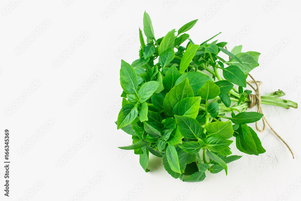 Obraz premium A bunch of green lemon basil on a white concrete table against a brick wall background