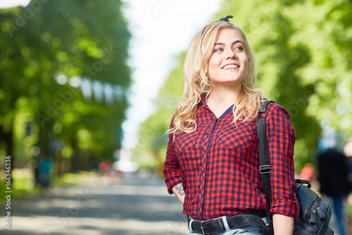 Portrait of beautiful young woman enjoying walk in park on sunny summer day