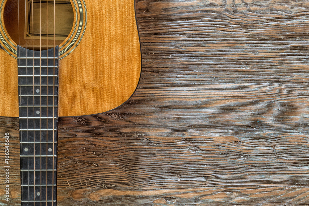 Obraz premium Acoustic guitar against a wooden background with copy space