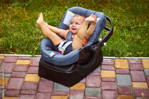 Infant baby seat in modern car seat in a park. New born child traveling by car. Child safety on the road. Safe way to travel with young kids. Fastened seat belts. Trip with an infant.