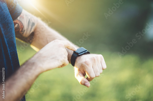 Close up of young running man tracking burned calories on electronic smart watch