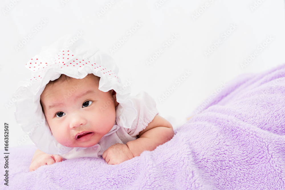 Portrait of a little adorable infant baby girl lying on the tummy on the pillow with head band Portrait of a little adorable infant baby girl lying on the tummy on the pillow with head band