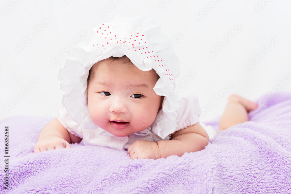 Portrait of a little adorable infant baby girl lying on the tummy on the pillow with head band Portrait of a little adorable infant baby girl lying on the tummy on the pillow with head band