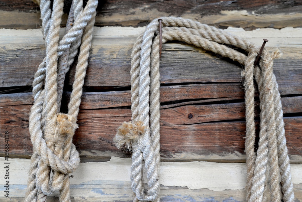 Old rope suspended on a wooden brown beam
