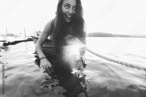 Brunette woman leans into the water on the bow of the boat