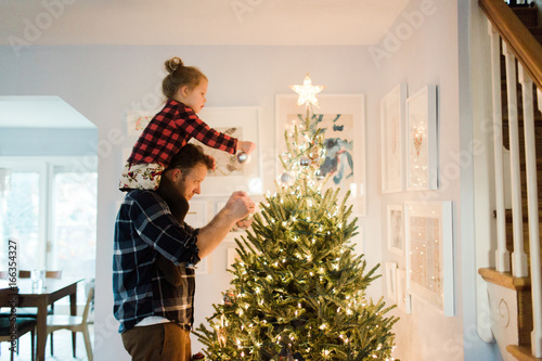 Father and daughter decorate a Christmas tree photo