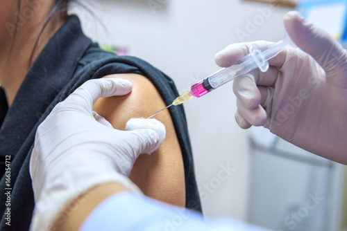 Close-up hands,nurses are vaccinations to patients using the syringe.Doctor vaccinating women in hospital.Are treated by the use of sterile injectable upper arm. injection