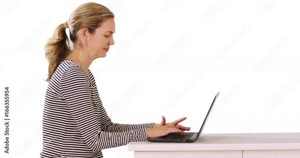 Profile of businesswoman sitting at desk using laptop in studio with copyspace Profile of businesswoman sitting at desk using laptop in studio with copyspace