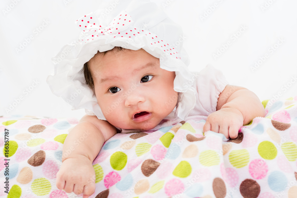 Portrait of a little adorable infant baby girl lying on the tummy on the pillow with head band Portrait of a little adorable infant baby girl lying on the tummy on the pillow with head band
