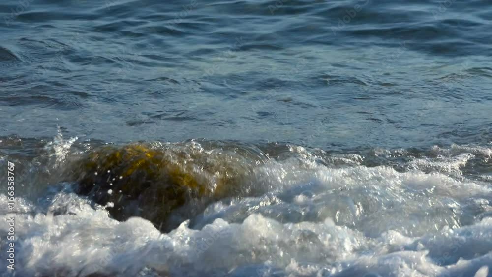 Sea pebbles closeup on a background of sea waves. Slow motion sea waves. Sea pebbles closeup on a background of sea waves. Slow motion sea waves.