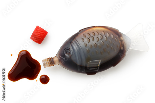 Open fish shaped take away soya sauce isolated on white from above. Spilled sauce.