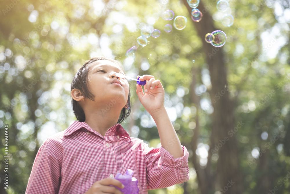 Cute Asian little girl Blowing soap bubble.Young Happy kid wear glasses and pink shirts in summer park. Cute Asian little girl Blowing soap bubble.Young Happy kid wear glasses and pink shirts in summer park.