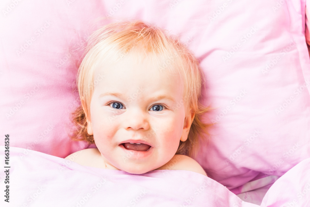 An awakened baby in a bed on a pink cushion An awakened baby in a bed on a pink cushion