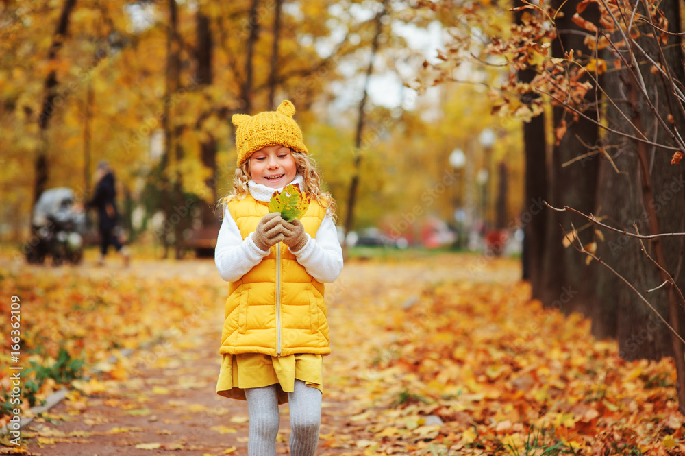 cute toddler girl playing with leaves in autumn park on the walk, wearing fashion yellow outfit cute toddler girl playing with leaves in autumn park on the walk, wearing fashion yellow outfit