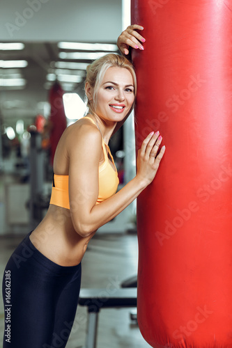 Tired young woman training with punching bag after training at gym