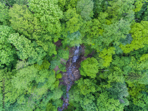 Fototapeta Naklejka Na Ścianę i Meble -  Hidden in the forest waterfall. Aerial top view.