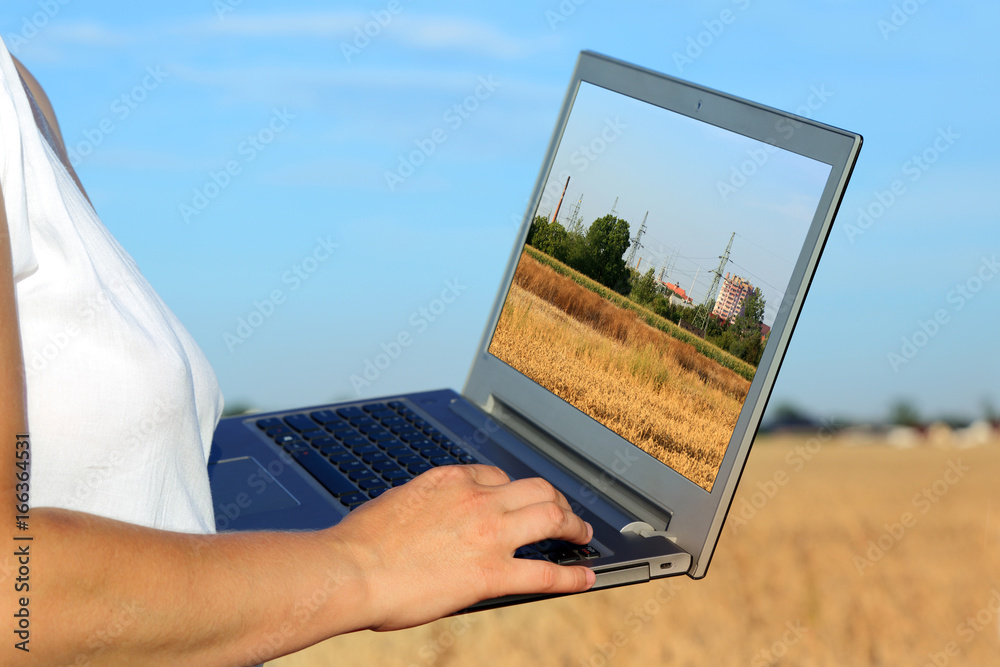 Kobieta z laptopem w krajobrazie wiejskim. - obrazy, fototapety, plakaty 