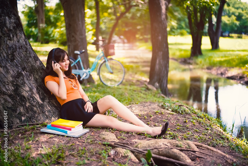 Girl relax under the tree in the park with headphones, relax concept