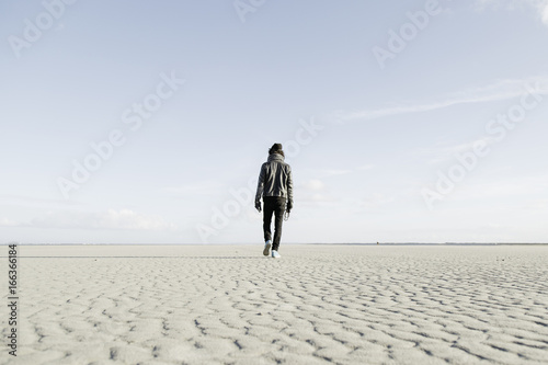 Hip young guy walking alone on the beach. photo