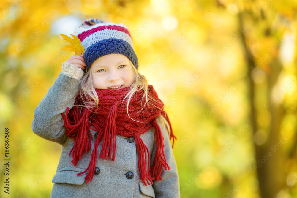 Cute little girl having fun on beautiful autumn day. Happy child playing in autumn park. Kid gathering yellow fall foliage. Cute little girl having fun on beautiful autumn day. Happy child playing in autumn park. Kid gathering yellow fall foliage.