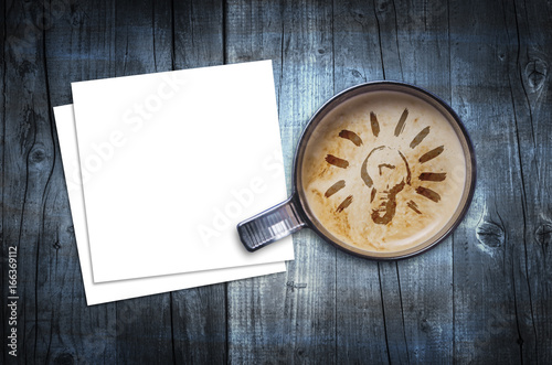 Fresh idea. Cup of fresh espresso with bulb sign and blank note paper  view from above.
