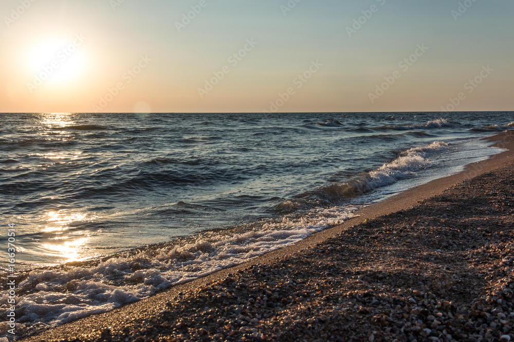 Sea waves at sunset at the shore with seashells. Beautiful background. Sea waves at sunset at the shore with seashells. Beautiful background.