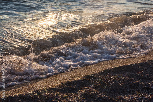 Background of a sea wave by the shore at sunset.