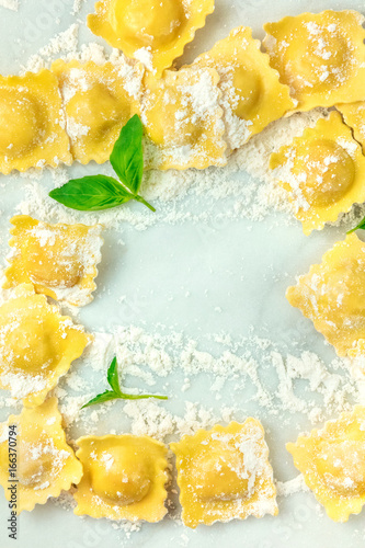 Overhead photo of ravioli with flour and basil leaves