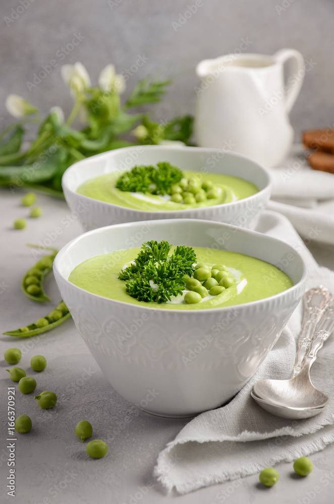 Green pea soup in bowls on grey concrete or stone background, selective focus Green pea soup in bowls on grey concrete or stone background, selective focus