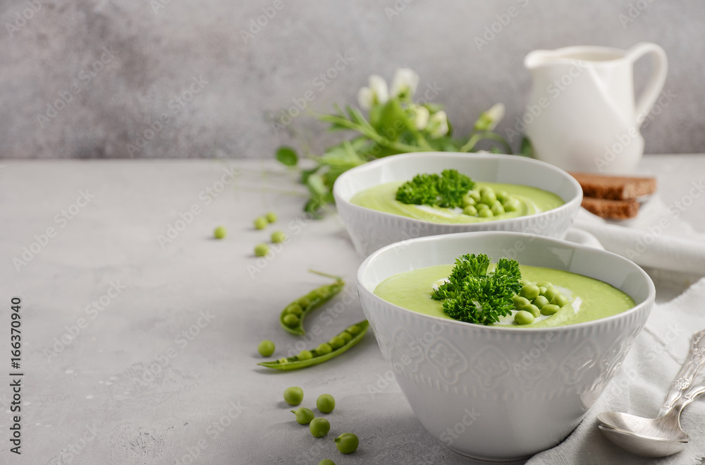 Green pea soup in bowls on grey concrete or stone background, selective focus, copy space Green pea soup in bowls on grey concrete or stone background, selective focus, copy space