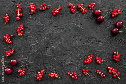 Berry frame. Red currant and cherry on black table background top view copyspace