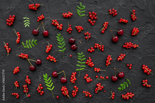 Berry pattern. Red currant, cherry and leaves on black table background top view
