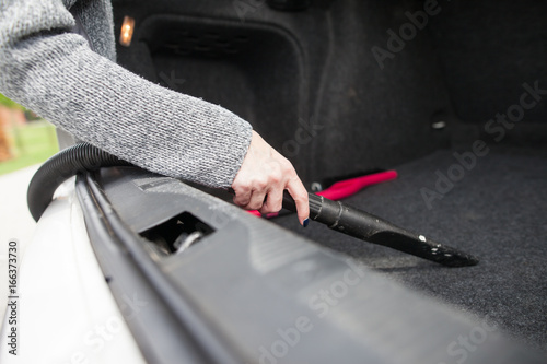 Young woman hands vacuuming car trunk of the dust