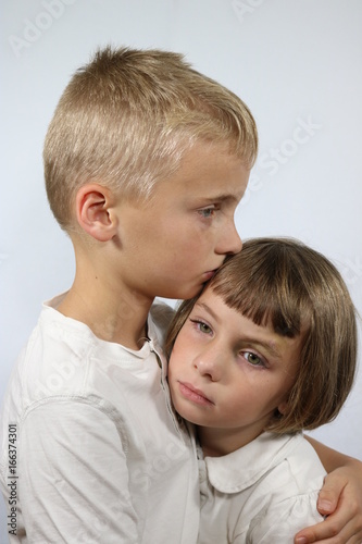 Portrait of brother comforting little sister with black eye
