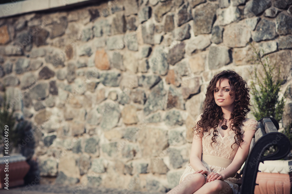 Brown-eyed brunette girl sitting on a bench