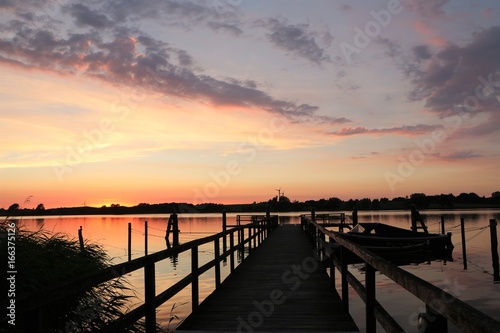 malerischer Abendhimmel an einem Steg mit Boot kurz nach Sonnenuntergang
