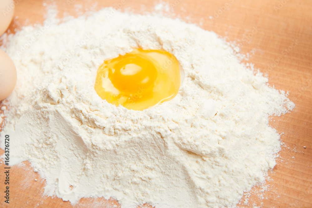 Yolk on flour heap closeup, wooden background, raw food Yolk on flour heap closeup, wooden background, raw food