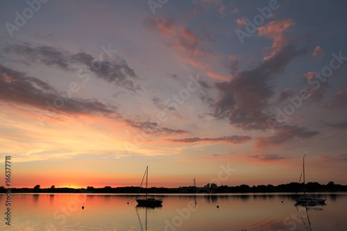 magisches Lich mit angestrahlten Wolken am malerischen Abendhimmel, Segelboot auf der Schlei