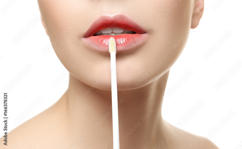 Fototapeta premium Young woman applying lip gloss, closeup