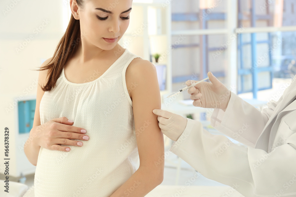 Young pregnant woman receiving vaccination in clinic Young pregnant woman receiving vaccination in clinic